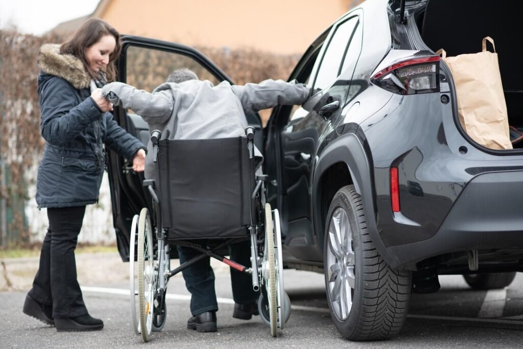 Occupational therapist assisting wheelchair user with safe car transfer in Darwin NT.